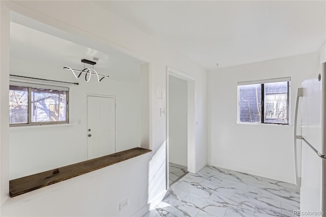 interior space with white refrigerator, a healthy amount of sunlight, and a chandelier