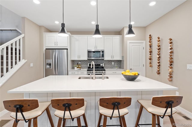 239 W Jamison Ct, Littleton, CO 80120 - kitchen with stainless steel appliances, a sink, backsplash, a kitchen breakfast bar, and recessed lighting