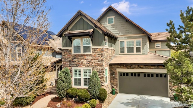 craftsman-style home featuring an attached garage, board and batten siding, stone siding, and concrete driveway