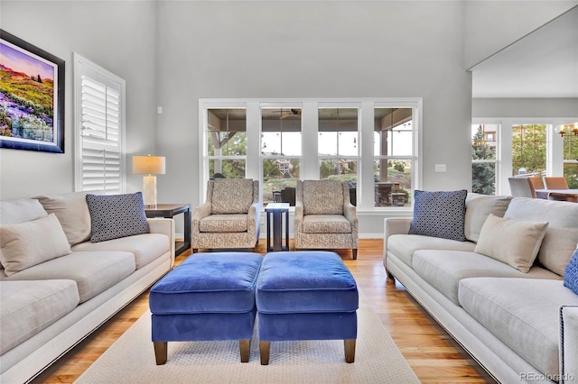 living area with a wealth of natural light, wood finished floors, and a towering ceiling