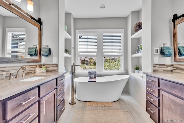 full bath featuring vanity, tasteful backsplash, built in shelves, and a soaking tub