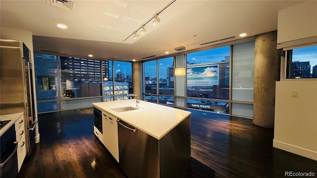 kitchen featuring sink, a center island with sink, dark hardwood / wood-style flooring, pendant lighting, and black appliances