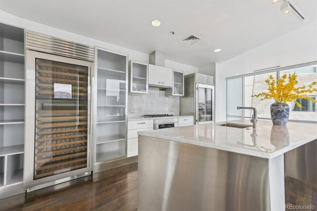 kitchen with sink, white cabinets, dark hardwood / wood-style flooring, decorative backsplash, and light stone countertops