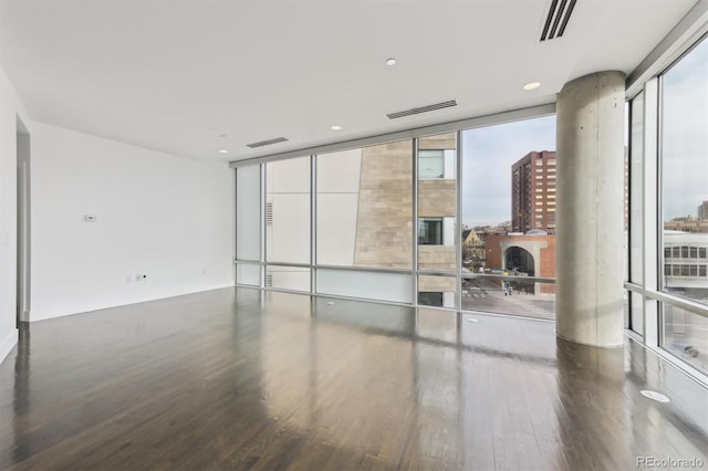 empty room with a wall of windows, wood-type flooring, and a fireplace