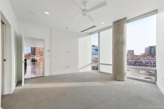 unfurnished room with plenty of natural light, floor to ceiling windows, ceiling fan, and carpet