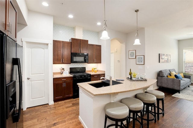 kitchen with a breakfast bar area, sink, pendant lighting, and black appliances