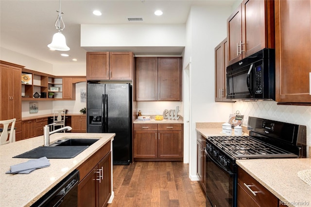 kitchen featuring sink, dark wood-type flooring, light stone counters, black appliances, and decorative light fixtures