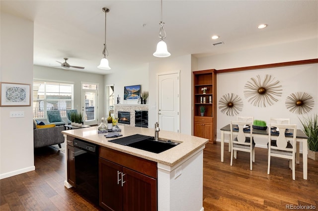 kitchen featuring sink, decorative light fixtures, dark hardwood / wood-style flooring, black dishwasher, and an island with sink