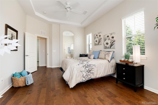 bedroom with ceiling fan, dark hardwood / wood-style floors, and a raised ceiling