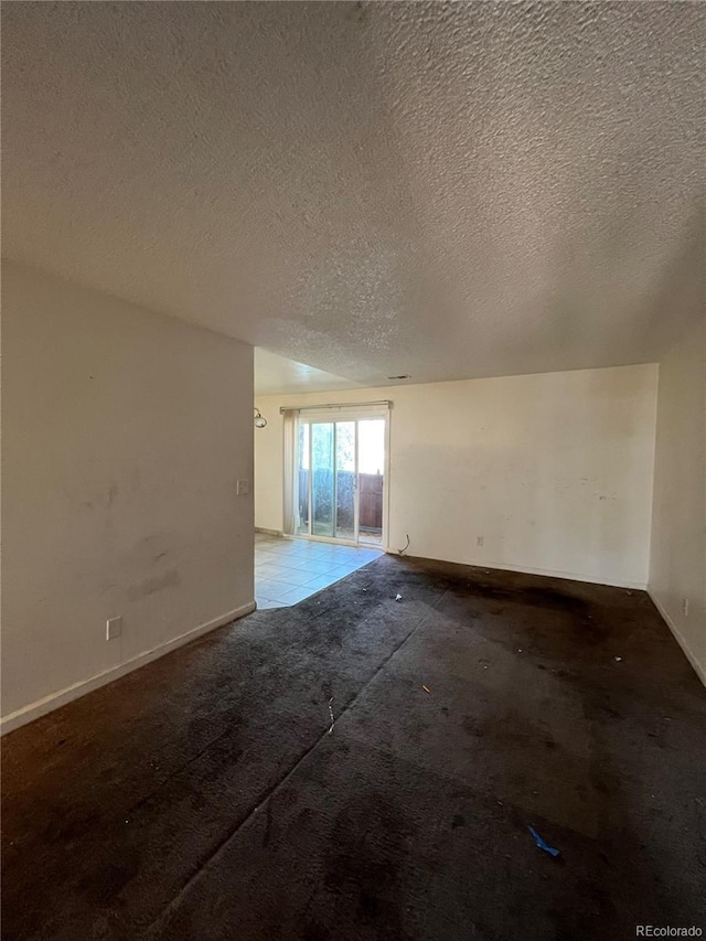 spare room featuring light carpet and a textured ceiling