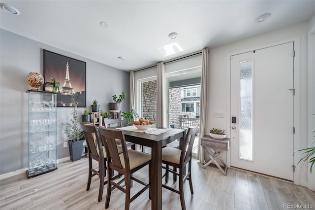 dining area featuring light wood-type flooring and baseboards