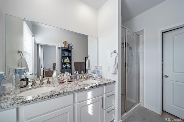 bathroom with double vanity, a shower stall, a sink, and ensuite bathroom