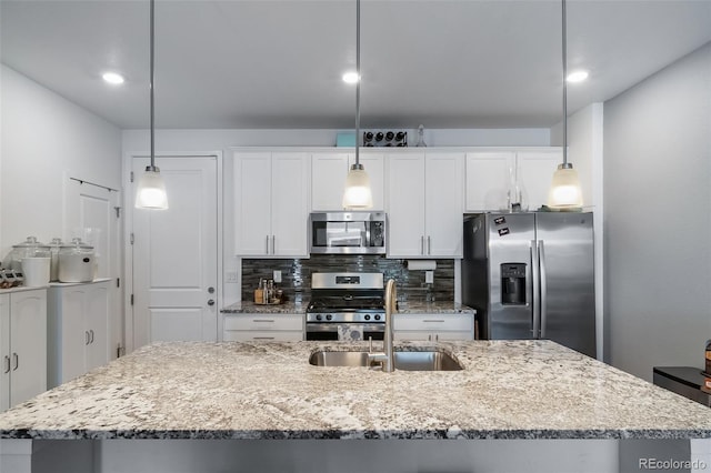 kitchen featuring a center island with sink, tasteful backsplash, appliances with stainless steel finishes, white cabinets, and a sink