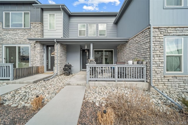 doorway to property featuring stone siding and a porch