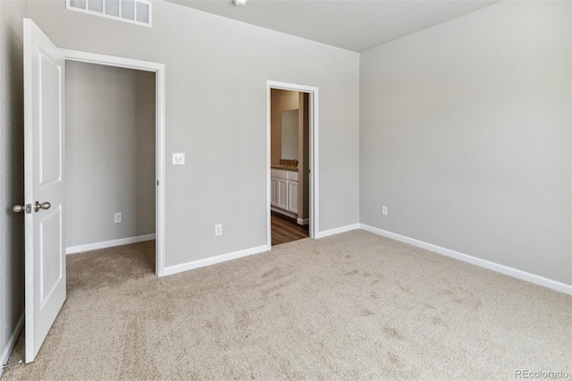 unfurnished bedroom with carpet floors, baseboards, and connected bathroom
