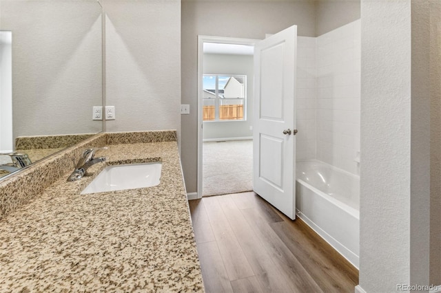 bathroom featuring wood finished floors, vanity, and bathing tub / shower combination