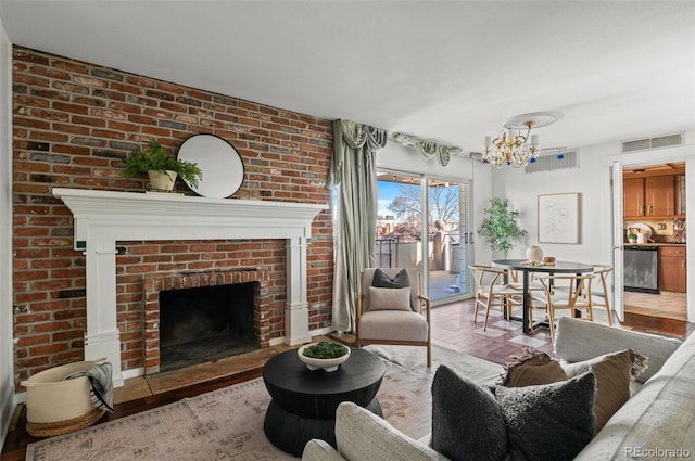 living room featuring brick wall, a brick fireplace, and a notable chandelier