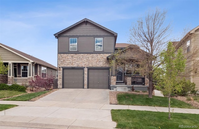 view of front of property with covered porch, driveway, a garage, a front lawn, and stone siding