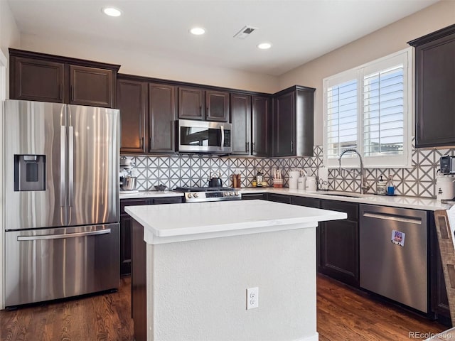 kitchen featuring dark brown cabinetry, appliances with stainless steel finishes, a sink, light countertops, and dark wood finished floors