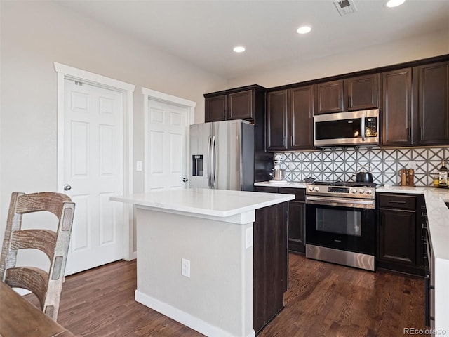 kitchen featuring visible vents, light countertops, tasteful backsplash, dark wood finished floors, and stainless steel appliances