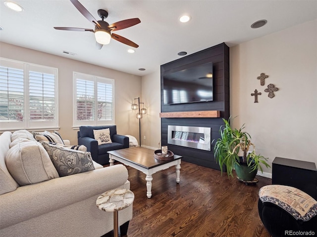 living area with visible vents, wood finished floors, a fireplace, baseboards, and a ceiling fan