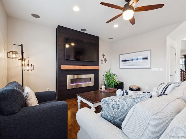 living room featuring recessed lighting, a ceiling fan, dark wood-style flooring, and a large fireplace