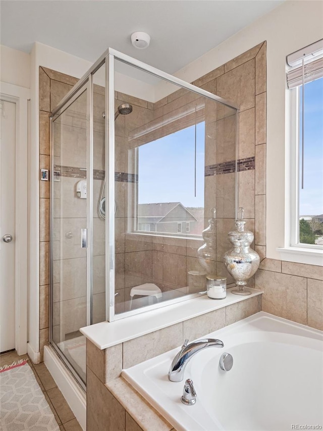 full bathroom featuring plenty of natural light, a shower stall, and a bath