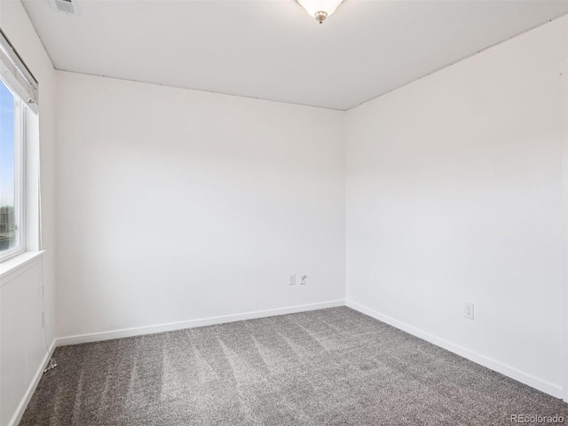 carpeted spare room featuring a healthy amount of sunlight and baseboards