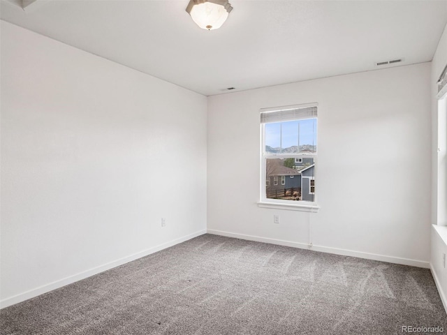 carpeted spare room featuring baseboards and visible vents