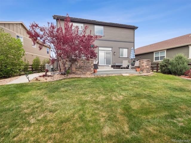 rear view of property with a lawn, a patio, and stone siding
