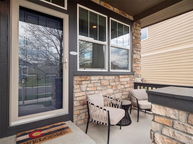 doorway to property featuring a porch and stone siding