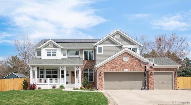 view of front facade with fence, a porch, a front yard, roof mounted solar panels, and driveway