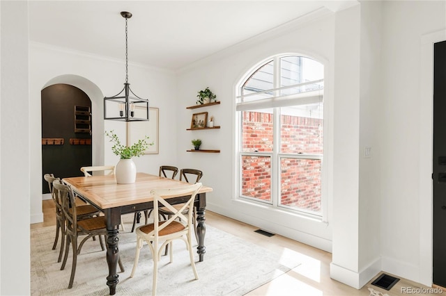 dining room featuring an inviting chandelier, arched walkways, ornamental molding, and visible vents