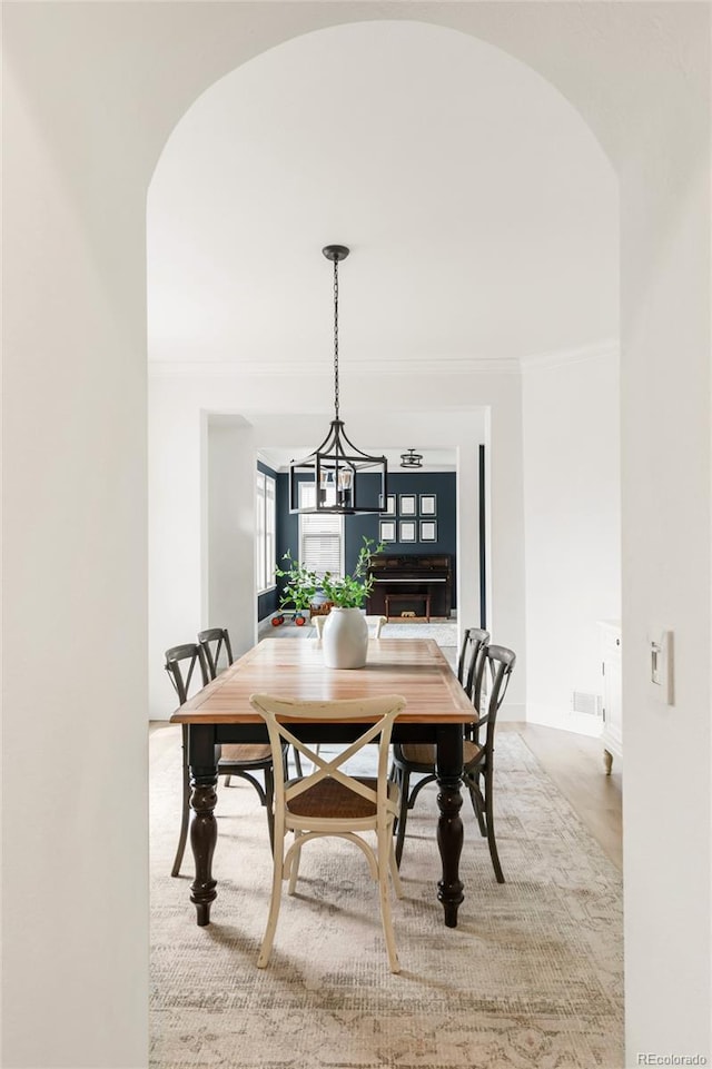dining room featuring crown molding, arched walkways, baseboards, and an inviting chandelier