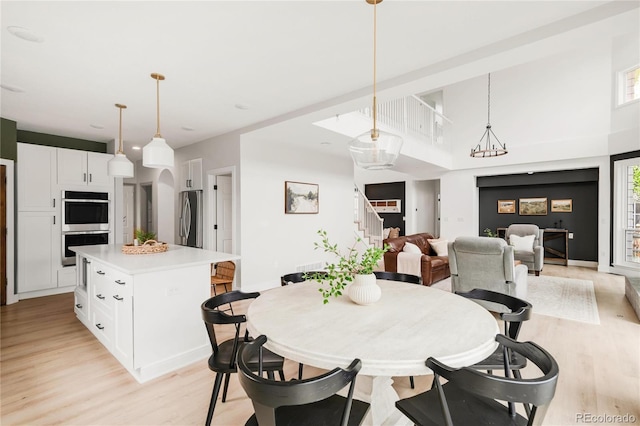 dining space with baseboards, light wood finished floors, and stairs