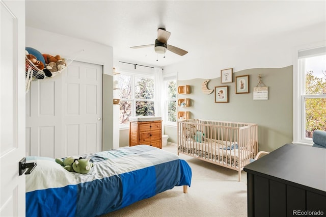 carpeted bedroom with a closet, ceiling fan, and multiple windows