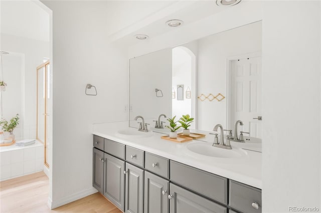 full bathroom with double vanity, a sink, and wood finished floors