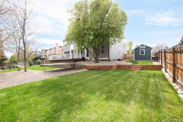 view of yard featuring a residential view, a trampoline, a storage shed, a fenced backyard, and an outbuilding
