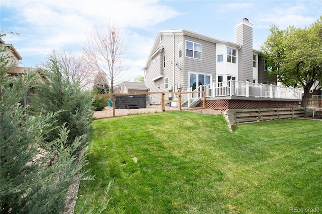 back of house with a lawn, a deck, and a chimney