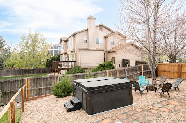 view of patio / terrace with a fenced backyard, a hot tub, and an outdoor fire pit