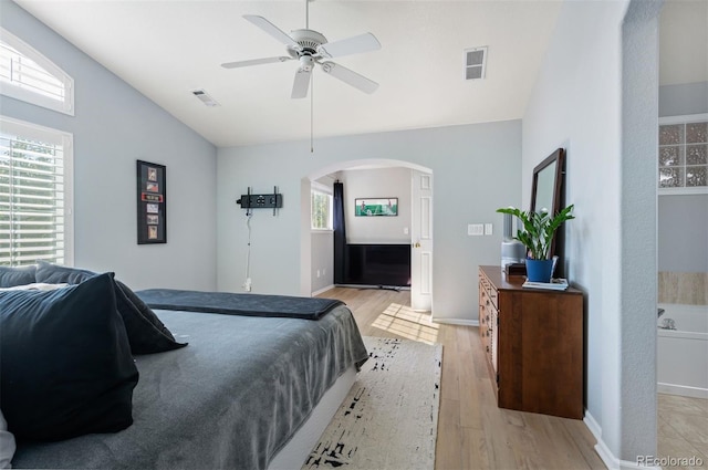 bedroom with ensuite bathroom, multiple windows, light hardwood / wood-style floors, and ceiling fan