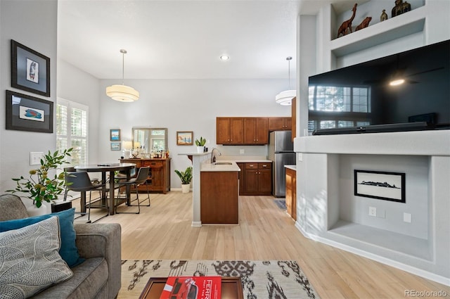 kitchen featuring freestanding refrigerator, light countertops, light wood-style flooring, baseboards, and open floor plan