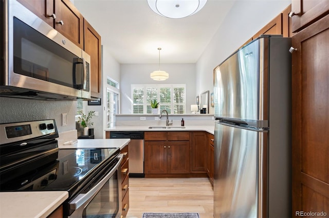 kitchen featuring appliances with stainless steel finishes, a sink, light wood-style flooring, and light countertops