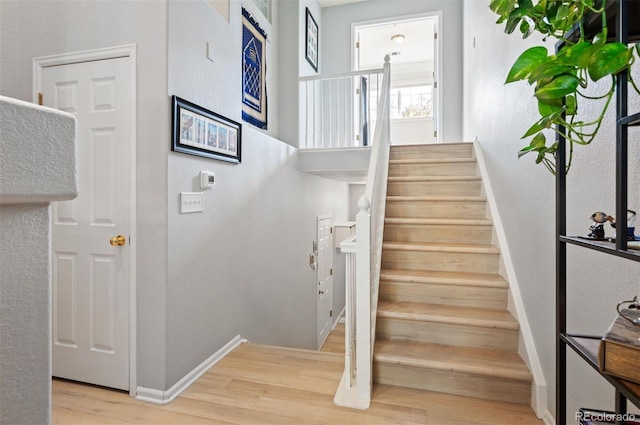 stairway with wood finished floors, baseboards, and a textured wall