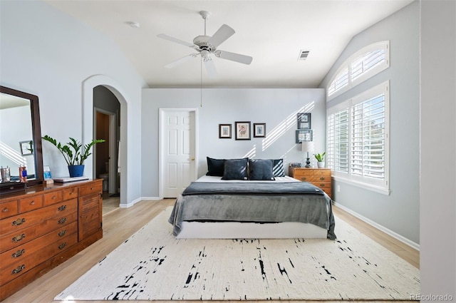bedroom featuring vaulted ceiling, light wood finished floors, arched walkways, baseboards, and ceiling fan