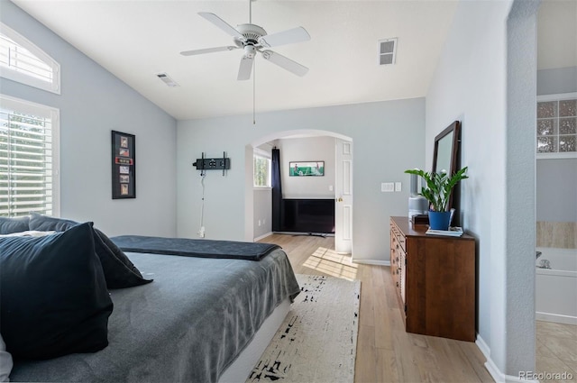 bedroom with arched walkways, light wood-type flooring, vaulted ceiling, baseboards, and ceiling fan