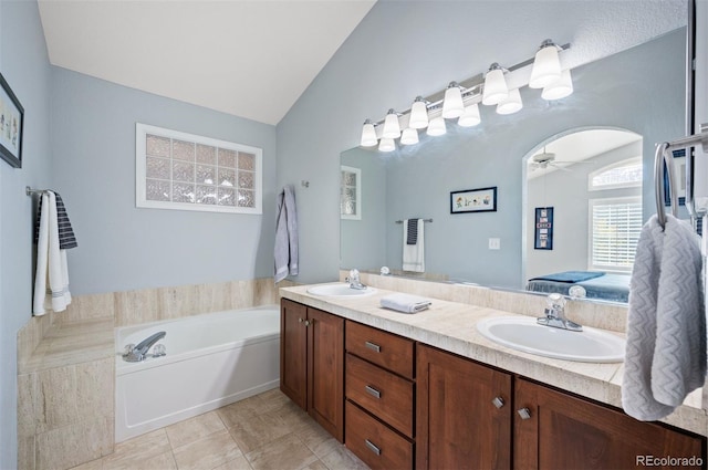ensuite bathroom featuring lofted ceiling, double vanity, a ceiling fan, a garden tub, and tile patterned floors