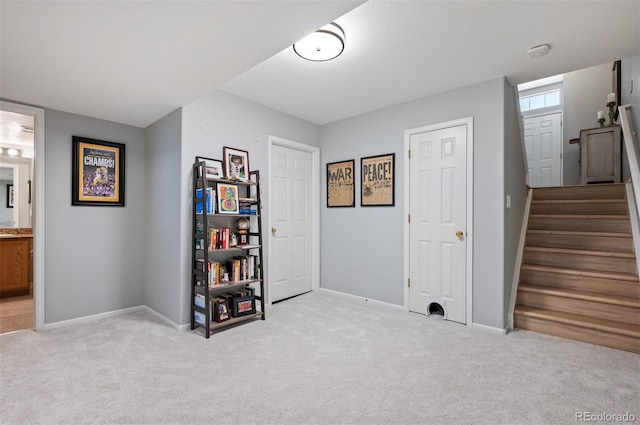 interior space featuring light colored carpet, baseboards, and stairway