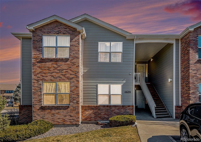 view of front facade featuring stairway and brick siding