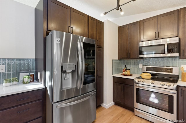 kitchen featuring a textured ceiling, stainless steel appliances, light hardwood / wood-style flooring, and tasteful backsplash